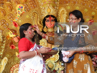 Hindu women apply ''sindhur,'' or vermillion powder, on each other's faces after worshipping the idol of the Hindu goddess Durga before it i...