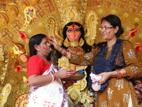 Hindu women apply ''sindhur,'' or vermillion powder, on each other's faces after worshipping the idol of the Hindu goddess Durga before it i...