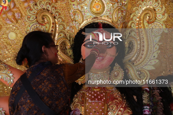 A Hindu woman performs worship of the idol of the Hindu goddess Durga before it is immersed in the Hooghly River during the Durga Puja festi...