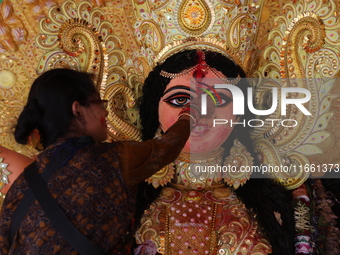 A Hindu woman performs worship of the idol of the Hindu goddess Durga before it is immersed in the Hooghly River during the Durga Puja festi...