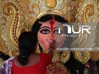 A Hindu woman performs worship of the idol of the Hindu goddess Durga before it is immersed in the Hooghly River during the Durga Puja festi...