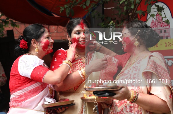 Hindu women apply ''sindhur,'' or vermillion powder, on each other's faces after worshipping the idol of the Hindu goddess Durga before it i...