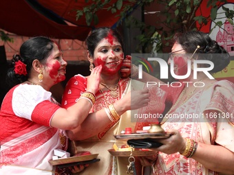 Hindu women apply ''sindhur,'' or vermillion powder, on each other's faces after worshipping the idol of the Hindu goddess Durga before it i...