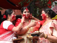 Hindu women apply ''sindhur,'' or vermillion powder, on each other's faces after worshipping the idol of the Hindu goddess Durga before it i...