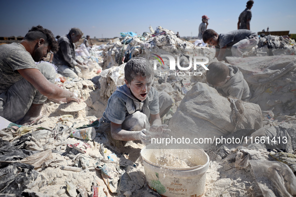 A photo shows Palestinian youths collecting remains of spoiled flour discarded in a makeshift landfill near the tents of displaced people in...