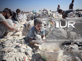 A photo shows Palestinian youths collecting remains of spoiled flour discarded in a makeshift landfill near the tents of displaced people in...