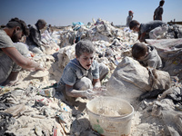 A photo shows Palestinian youths collecting remains of spoiled flour discarded in a makeshift landfill near the tents of displaced people in...