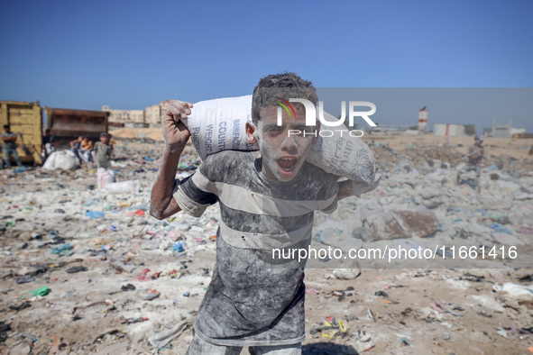 A photo shows Palestinian youths collecting remains of spoiled flour discarded in a makeshift landfill near the tents of displaced people in...