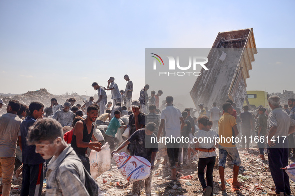 A photo shows Palestinian youths collecting remains of spoiled flour discarded in a makeshift landfill near the tents of displaced people in...