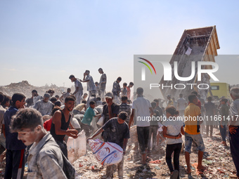 A photo shows Palestinian youths collecting remains of spoiled flour discarded in a makeshift landfill near the tents of displaced people in...