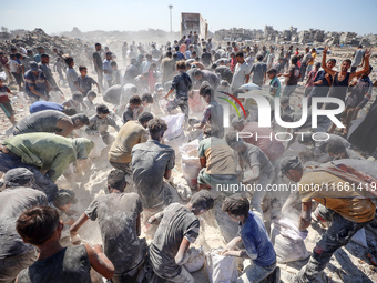 A photo shows Palestinian youths collecting remains of spoiled flour discarded in a makeshift landfill near the tents of displaced people in...