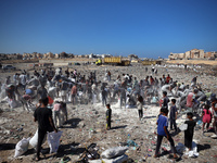 A photo shows Palestinian youths collecting remains of spoiled flour discarded in a makeshift landfill near the tents of displaced people in...