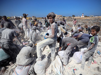 A photo shows Palestinian youths collecting remains of spoiled flour discarded in a makeshift landfill near the tents of displaced people in...