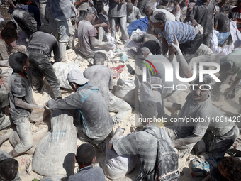 A photo shows Palestinian youths collecting remains of spoiled flour discarded in a makeshift landfill near the tents of displaced people in...