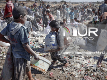 A photo shows Palestinian youths collecting remains of spoiled flour discarded in a makeshift landfill near the tents of displaced people in...