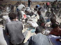 A photo shows Palestinian youths collecting remains of spoiled flour discarded in a makeshift landfill near the tents of displaced people in...