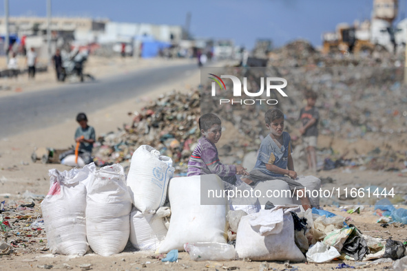 A photo shows Palestinian youths collecting remains of spoiled flour discarded in a makeshift landfill near the tents of displaced people in...