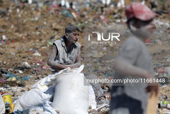 A photo shows Palestinian youths collecting remains of spoiled flour discarded in a makeshift landfill near the tents of displaced people in...