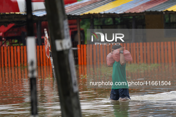 A man carries food during the flood in Kelaniya, Sri Lanka, on October 13, 2024. The adverse weather affects approximately 76,218 people fro...