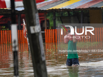 A man carries food during the flood in Kelaniya, Sri Lanka, on October 13, 2024. The adverse weather affects approximately 76,218 people fro...