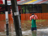 A man carries food during the flood in Kelaniya, Sri Lanka, on October 13, 2024. The adverse weather affects approximately 76,218 people fro...