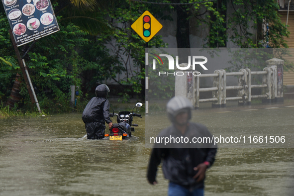 A man pushes a motorcycle on the flooded road in Kelaniya, Sri Lanka, on October 13, 2024. The adverse weather affects approximately 76,218...