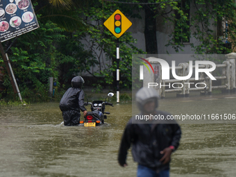 A man pushes a motorcycle on the flooded road in Kelaniya, Sri Lanka, on October 13, 2024. The adverse weather affects approximately 76,218...