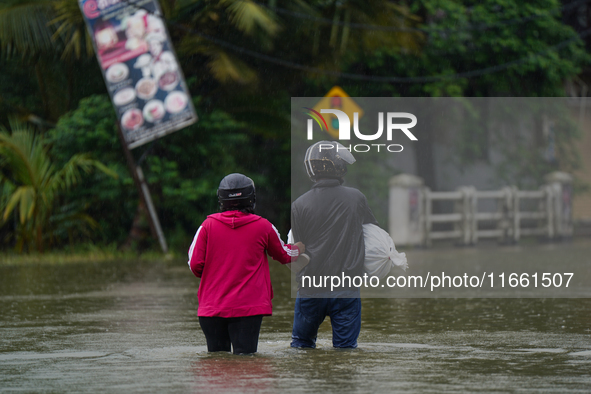 People walk on the flooded road in Kelaniya, Sri Lanka, on October 13, 2024. The adverse weather affects approximately 76,218 people from 18...