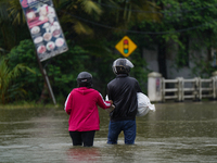 People walk on the flooded road in Kelaniya, Sri Lanka, on October 13, 2024. The adverse weather affects approximately 76,218 people from 18...