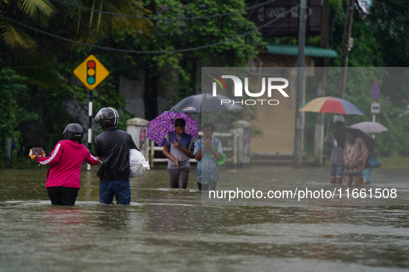 People walk on the flooded road in Kelaniya, Sri Lanka, on October 13, 2024. The adverse weather affects approximately 76,218 people from 18...