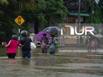 People walk on the flooded road in Kelaniya, Sri Lanka, on October 13, 2024. The adverse weather affects approximately 76,218 people from 18...