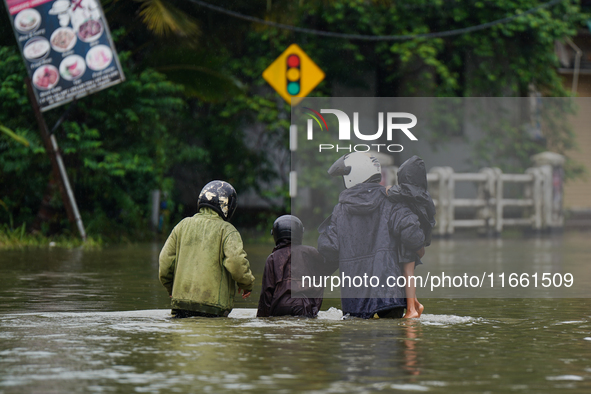 People walk on the flooded road in Kelaniya, Sri Lanka, on October 13, 2024. The adverse weather affects approximately 76,218 people from 18...