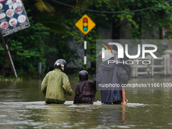 People walk on the flooded road in Kelaniya, Sri Lanka, on October 13, 2024. The adverse weather affects approximately 76,218 people from 18...