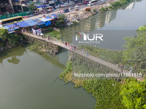 An aerial view shows hundreds of people in Dhaka, Bangladesh, using the makeshift bamboo bridge over the canal at Banasree in the capital ci...