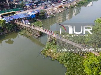 An aerial view shows hundreds of people in Dhaka, Bangladesh, using the makeshift bamboo bridge over the canal at Banasree in the capital ci...