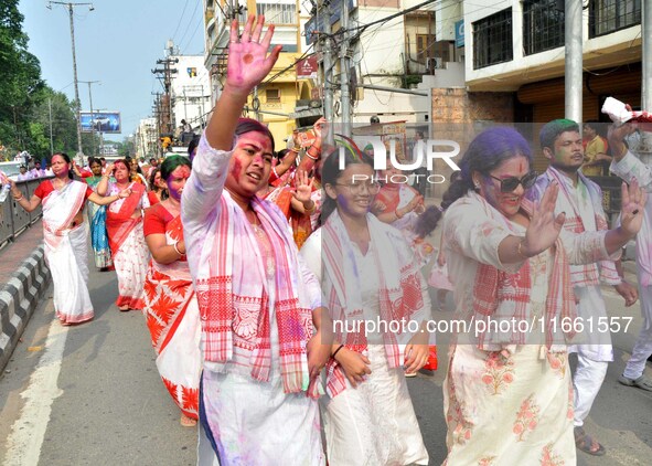 Devotees with color-smeared faces dance on a road during a procession for immersion on the last day of the Durga Puja festival in Guwahati,...