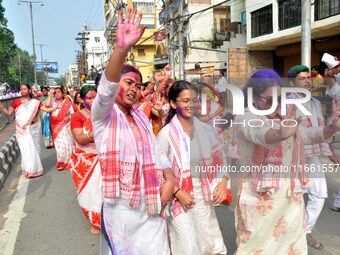 Devotees with color-smeared faces dance on a road during a procession for immersion on the last day of the Durga Puja festival in Guwahati,...