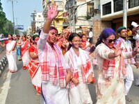 Devotees with color-smeared faces dance on a road during a procession for immersion on the last day of the Durga Puja festival in Guwahati,...