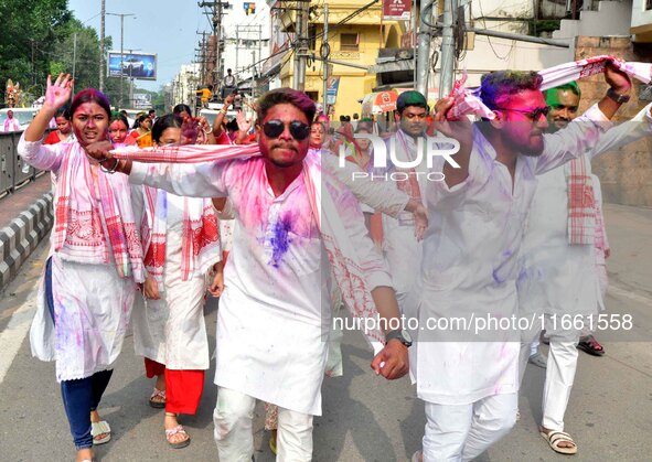 Devotees with color-smeared faces dance on a road during a procession for immersion on the last day of the Durga Puja festival in Guwahati,...