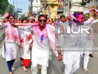 Devotees with color-smeared faces dance on a road during a procession for immersion on the last day of the Durga Puja festival in Guwahati,...