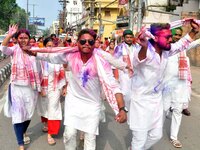 Devotees with color-smeared faces dance on a road during a procession for immersion on the last day of the Durga Puja festival in Guwahati,...