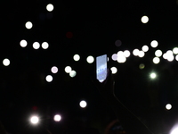 Spectators use telephones to light shows and attend a trumpet concert at the opening night of the light festival in Lyon, France, on October...