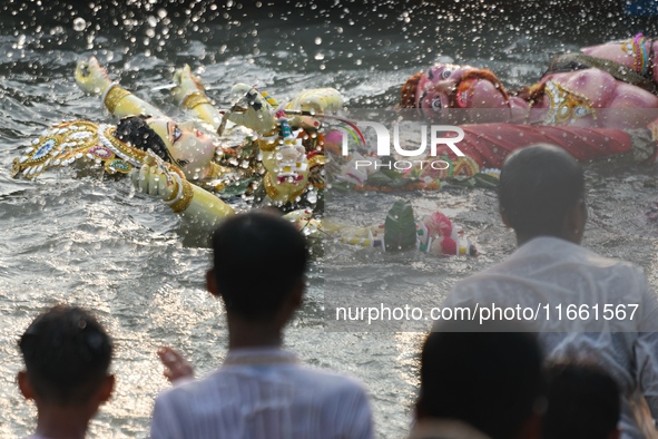 Hindu devotees immerse a clay idol of the Hindu goddess Durga in the Buriganga River on the final day of the Durga Puja festival in Dhaka, B...