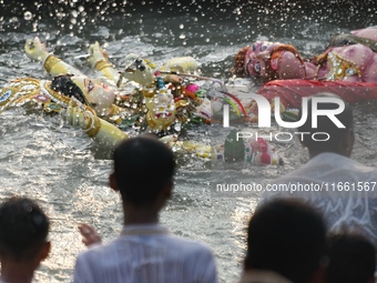 Hindu devotees immerse a clay idol of the Hindu goddess Durga in the Buriganga River on the final day of the Durga Puja festival in Dhaka, B...