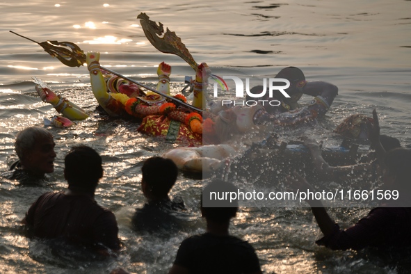 Hindu devotees immerse a clay idol of the Hindu goddess Durga in the Buriganga River on the final day of the Durga Puja festival in Dhaka, B...