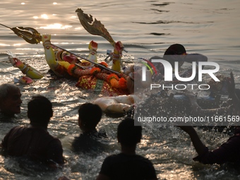 Hindu devotees immerse a clay idol of the Hindu goddess Durga in the Buriganga River on the final day of the Durga Puja festival in Dhaka, B...