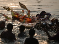 Hindu devotees immerse a clay idol of the Hindu goddess Durga in the Buriganga River on the final day of the Durga Puja festival in Dhaka, B...