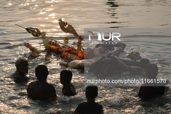 Hindu devotees immerse a clay idol of the Hindu goddess Durga in the Buriganga River on the final day of the Durga Puja festival in Dhaka, B...