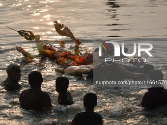 Hindu devotees immerse a clay idol of the Hindu goddess Durga in the Buriganga River on the final day of the Durga Puja festival in Dhaka, B...