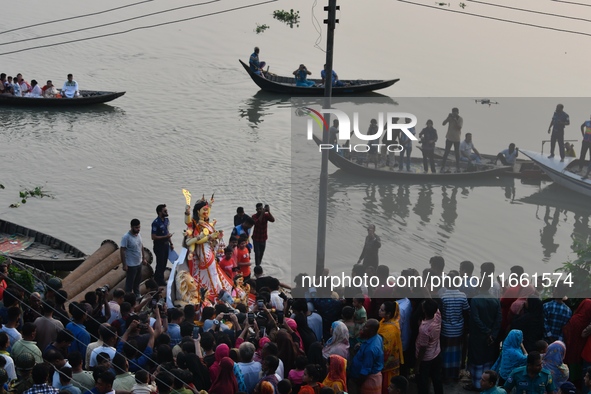 Hindu devotees immerse a clay idol of the Hindu goddess Durga in the Buriganga River on the final day of the Durga Puja festival in Dhaka, B...